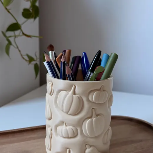 Pumpkin organizer filled with pens on a wooden tray