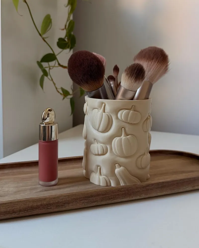 Cream pumpkin-patterned cup holding makeup brushes