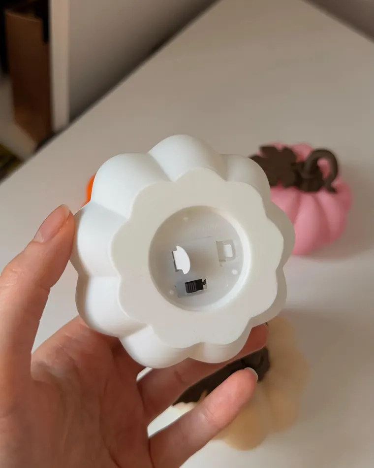 Tati's hand holding a white pumpkin night light